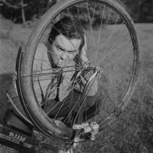 "Porträt eines Mannes im Wald bei der Reparatur eines Fahrradreifens." (1955)