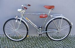 "Brandenburg" von 1958. Ursprüngliche Farbe des Rahmens Pink-Metallic, durch Lichteinfluß beinahe vollständig zu Grau verblichen. Rahmen ergänzt mit zeitgenössischen Anbauteilen. Zusätzlich ist eine seltene DDR-Schutzblechfigur auf dem vorderen Schutzblech angebracht.