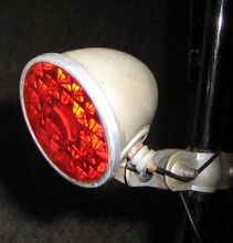 Rücklicht Typ RE 1 Zeitraum: ca. 1952/53 bis 1956 Verwendung: Mifa Sporträder und Mifa Tourenräder Material: Stahl, Glas, Aluminium Farben/Varianten: silber (im Bild), schwarz Bemerkungen: zur Rahmenmontage, Lampeneinsatz laufradseitig