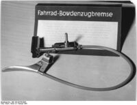"Massenbedarfsgüter aus dem VEB Büromaschinenwerk Karl-Marx-Stadt. In diesem Jahr werden 300.000 der begehrten Fahrrad-Bowdenzugbremsen hergestellt." (Februar 1955) Text des Pappaufstellers: "Dieser vielbegehrte Artikel wurde von der HV [Hauptverwaltung] vorgeschlagen. Die Bremse hat den Vorteil des leichten Gewichtes und der guten Bremsleistung. Die Oberfläche ist gegen Rostbildung verkupfert, vernickelt und verchromt. Der bunte Isolierschlauch verhindert das Eindringen von Wasser in den Bowdenzug. Er wird [unleserlich] und in den Farben grau, rot, blau und braun geliefert. Die Bremse ist an [unleserlich]."