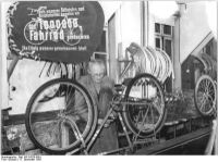 "Am 1. Oktober 1955 verließ das Millionste Fahrrad das volkseigene Möwewerk in Mühlhausen. Wer ist der Käufer des Möwe-Fahrrades mit dem Garantieschein-Nummer "1 Million", diese Frage beschäftigt die Kollegen des Betriebes, die ihre Produktion gegenüber der jährlichen Vorkriegsproduktion um 170% steigern konnte." Hier: Bandkontrolle der montierten Fahrräder. (Dezember 1955)