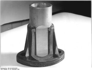 "Eine im Druckspritzverfahren hergestellte Aluminium-Tempergußverbindung.(aufgeschnitten). Sehr deutlich kann man die eingespritzte Gummischicht erkennen. Die Zerreißfestigkeit der Verbindung beträgt über 10 t." (Dezember 1956)