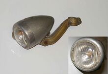 Zeitraum: 19xx bis 19xx Verwendung: Zubehör Material: Duroplast (schwarz, rot), Aluminium, Glas Ø Lichtaustritt: 55 mm Farben/Varianten: hammerschlag-silber, unlackiert (rotes Duroplast) Bemerkungen: Streuscheibe mit "Blaustern" gekennzeichnet, Lampenring aus dickwandigem Aluminium