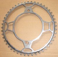 Diamant-Kettenblatt (Sportrad-Ausführung) Zeitraum: vrmtl. 1953/54 Verwendung: Diamant Sporträder Material: Stahl (verchromt) Befestigung: 2-Punkt-Befestigung (120mm Lochkreisdurchmesser) Größe: 48 Zähne Zahnbreite: 1/8" (??mm) Bemerkungen: vrmtl. Vorserien-Muster; charakteristische "Diamant-Kelche" als Streben