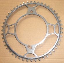 Diamant-Kettenblatt (Sportrad-Ausführung) Zeitraum: vrmtl. 1953/54 Verwendung: Diamant Sporträder Material: Stahl (verchromt) Befestigung: 2-Punkt-Befestigung Größe: 48 Zähne Zahnbreite: 2,8 mm (für 1/8"-Kette) Bemerkungen: vrmtl. Vorserien-Muster; charakteristische "Diamant-Kelche" als Streben