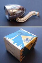 Scheinwerfer Typ FSW 60/85 Zeitraum: hier: 11/1959 Verwendung: vrmtl. Exportartikel Material: Stahlblech Bekannte Farben: verchromt Bemerkungen: Auf Oberseite geprägt mit IKA FEK Prüfzeichen 6v, 2,4 W, Streuscheibe geprägt mit FEK-Logo. Halter silbern lackert. Karton mit "Made in Germany Importé d'Allemagne 6 Volt 3 Watt" beschriftet.