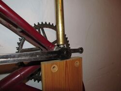 7. Keil ausschlagen Nach Abschluss der Vorbereitungen kann der Keil ausgeschlagen werden. Dazu wird das Brett senkrecht aufgestellt (eventuell von einer zweiten Person gehalten) und der Messingbolzen auf die Sicherungsmutter gesetzt. Der Bolzen reduziert das Risiko, die Kurbel oder andere Teile durch abgerutschte Fehlschläge zu beschädigen. In Abhängigkeit verschiedener Faktoren variiert die nötige Schlagenergie zum Lösen der Verbindung. Deshalb sollte zunächst "leicht" geschlagen werden und die Intensität danach langsam erhöht werden, bis der Keil nachgibt.