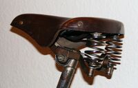 Tourensattel von LLM Zeitraum: 195x bis 195x (hier: 1951) Verwendung: alle Fahrradmarken (außer Simson) Decke: Leder, lackiert Gestell: Stahl, verchromt Bemerkungen: schmale Federn, gebogene Querstrebe