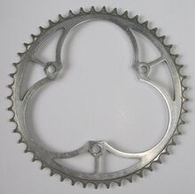 Sportkettenblatt (Leichtmetall-Ausführung) Zeitraum: vrmtl. Mitte 50er Jahre Verwendung: Diamant Luxus-Sporträder Material: Aluminium Befestigung: 3-Punkt-Befestigung (117mm Lochkreisdurchmesser) Größe: 49 Zähne Zahnbreite: 2,1mm (für 3/32"-Kette) Bemerkungen: ungerade Zähnezahl für gleichmäßigeren Verschleiß