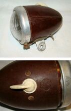 Scheinwerfer MGK 310a Zeitraum: ca. 1955 bis 1957 Verwendung: Zubehör Material: Duroplast, Aluminium, Glas Ø Lichtaustritt: 66 mm Bemerkungen: Betriebsnummer und Gütezeichen auf Gehäuse und Lampenring; frühe MGK-Scheinwerfer sind noch nicht mit "STOP Rümag" gekennzeichnet