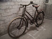 Modell S 8 von 1953/54, Gepäckträger und Kettenschutz nachgerüstet. Die Halterung für den Kettenschützer am Rahmen wurde nachträglich angelötet. Lenkergriffe und Klingel sind nicht original. Erkennbar ist der Lenker mit Plastemuffe und der silbern lackierte Gabelkopf. Hinteres Schutzblech mit ALARM-Reflektor.