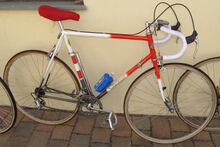 Vrmtl. in den 80ern umgebautes Rennrad. Ausgeführte Arbeiten: Kürzen des Hinterbaus, Begradigung der Gabel, neue Ausfallenden, Verlegung der Schaltzüge unter das Tretlager, Gewindehülsen für Flaschenhalter, Verlegung des hinteren Bremszuges, Mehrfarblackierung.