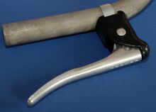 Rasant-Bremshebel für Trainingsbügel Zeitraum: 1989/90 Verwendung: Diamant Modell 35 721 und Diamant Modell 35 771; Zubehörteil Material: Aluminium Bemerkungen: Spezialausführung des Renn-Bremsgriffes für Trainingsbügel (Flachlenker); schwarze Kunststoff- beschichtung; ohne Zugentlaster