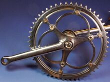 Tretkurbel (rechts) mit ovalem Querschnitt (mit abnehmbarem Kettenblatt) Zeitraum: 194x bis 1990 Verwendung: Mifa Modell 208, Zubehörteil Material: Stahl (verchromt) Kettenblattaufnahme: 3-Punkt-Befestigung (117 mm Lochkreisdurchmesser) Kurbellänge: 170 mm Bemerkungen: Blechglocke hinter der Kettenblattaufnahme