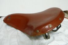 Sportsattel Nr. 421 VL (Möve) Zeitraum: 1960 bis ca. 1979 Verwendung: Tourensport- und Sporträder von Diamant, Mifa Sporträder Lederdecke: rotbraun lackiert Gestell: verchromt Bemerkungen: nunmehr ohne Plakette