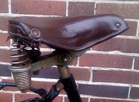 Tourensattel von ?? Zeitraum: 1954 bis 1957 Verwendung: sportliche Tourenräder von Simson Decke: Kunstleder Gestell: Stahl, verchromt Bemerkungen: Ausführungen für Damen- und Herrenräder, Regulierfedern, mit Simson-Plakette an der Rückseite, Hersteller unbekannt