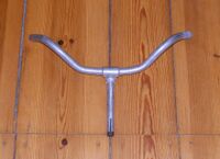 Tourenlenker des VEB Mechanische Werkstätten Wurzen-Deuben Zeitraum: spätestens 1955 bis mind. 1961 Verwendung: Zubehörteil Material: Aluminium Breite: 51 cm Schaftlänge: 15 cm Bemerkungen: Sportliche Form mit hochgezogenen Lenkerenden. Markante Lenkermuffe; Hersteller, Gütezeichen und Betriebsnummer auf Unterseite der Muffe geprägt.