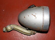 Zeitraum: 19xx bis 19xx Verwendung: Zubehör Material: Stahlblech, Aluminium, Glas Ø Lichtaustritt: 70 mm Farben/Varianten: silber Hammerschlag Bemerkungen: Streuglas und Reflektor aus einem Stück gegossen